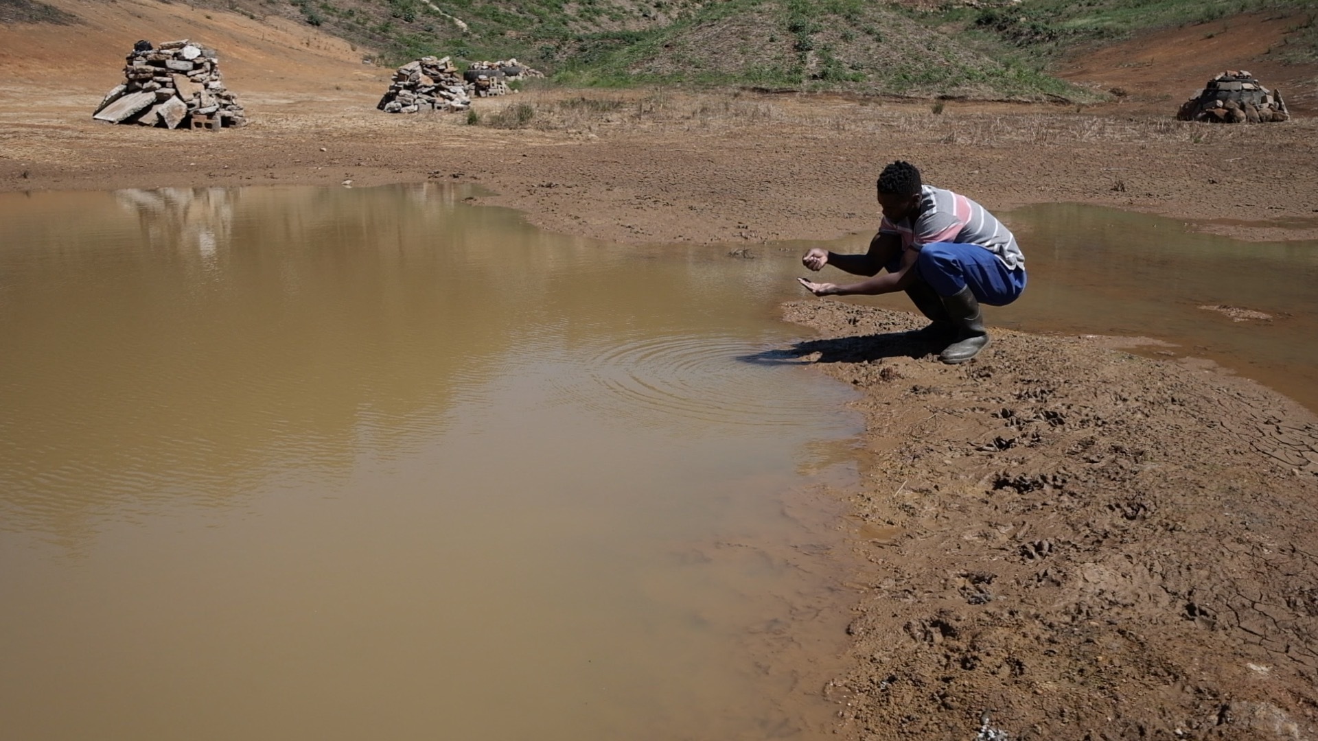 African-stock-video-of-rural-black-farmer-scooping-up-dirty-water-in-hand-2.jpg