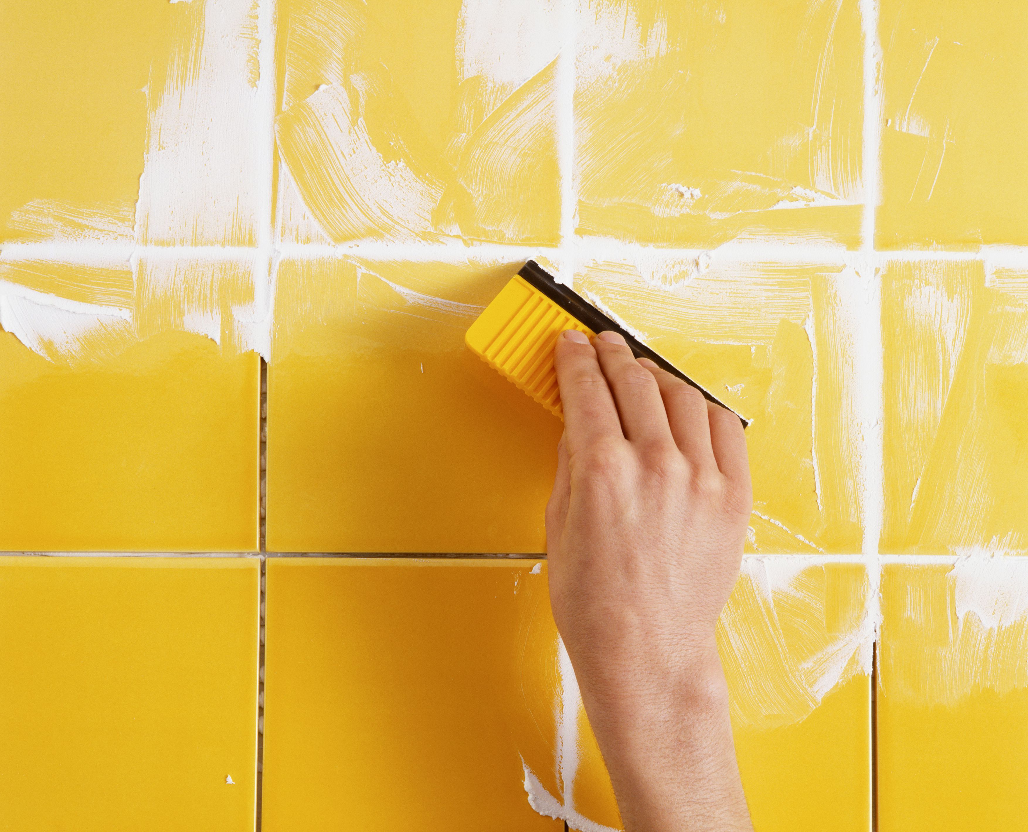 grout-being-applied-to-tiles-using-a-grout-spreader-81992491-582b44cb3df78c6f6aa728e4.jpg