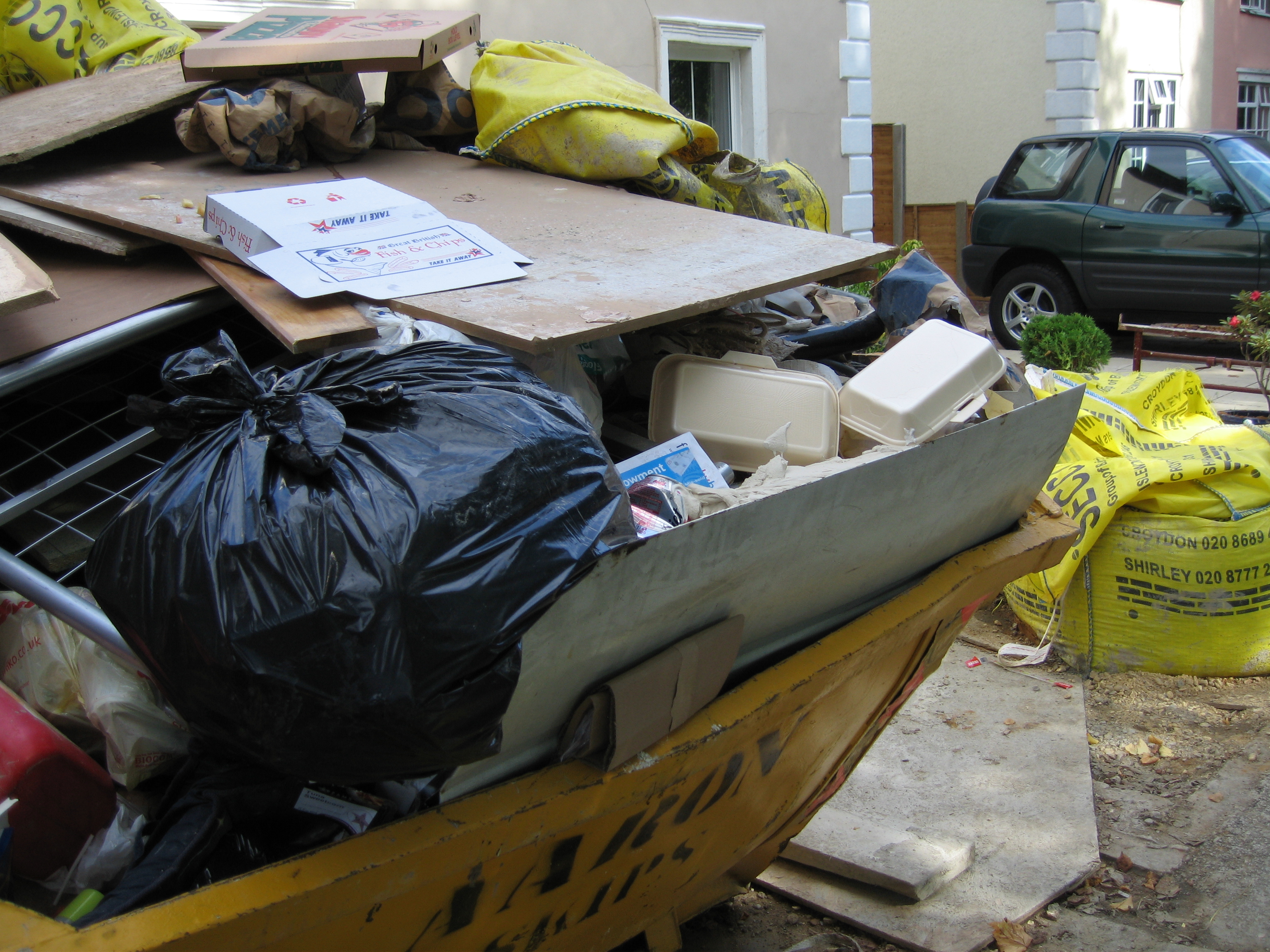 skip-builders-waste-rubbish-garbage-full-overflowing-outside-house-in-London-England-2-DHD.jpg