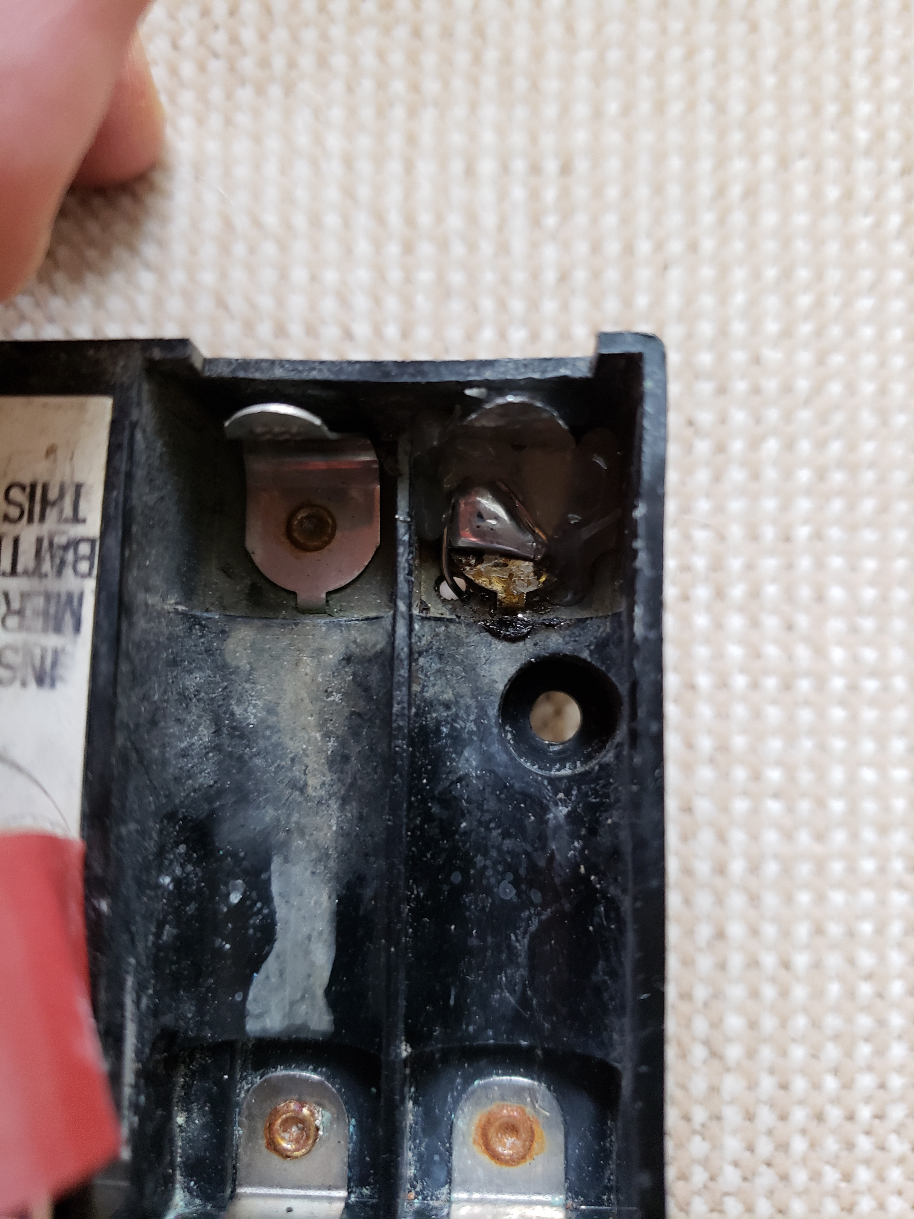 showing new metal battery terminal with wire going through hole and held in place with hot melt glue.jpg